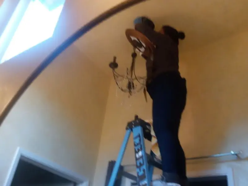 Electrician installing a chandelier in a Mandeville residence